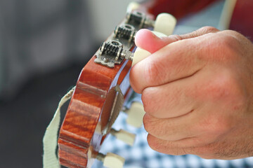 close-up of a man twisting Tuners or Tuning pegs.