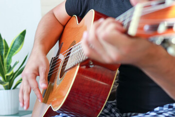 Close-up of a man playing guitar at home.