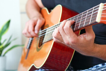 Close-up of playing guitar at home.