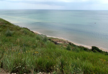 Azov sea coastal area with smooth green grass slope. Seashore view with blue sky horizon.