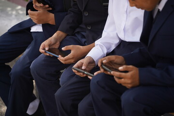 Almaty, Kazakhstan - 09.06.2023 : Children in school uniforms play mobile games on a bench near the...