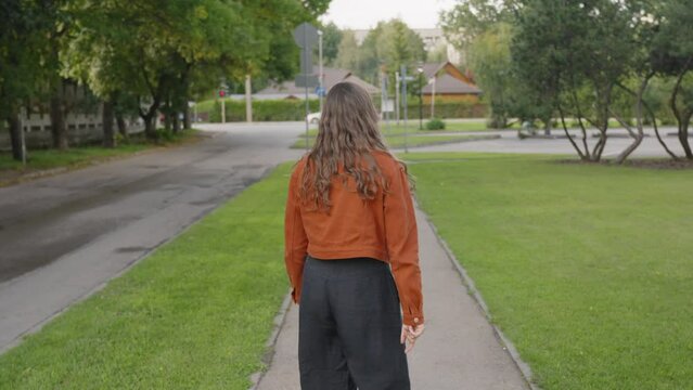 Woman waving at the camera saying goodbye then turns around and walks away, static