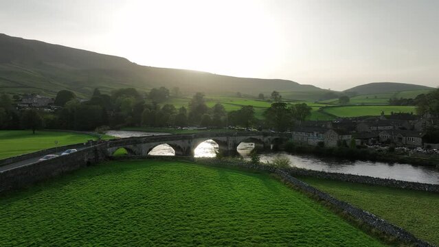 Beautiful sunset over bridge in Yorkshire dales, United Kindgom. Tracking Forward as a group of people walk over bridge.