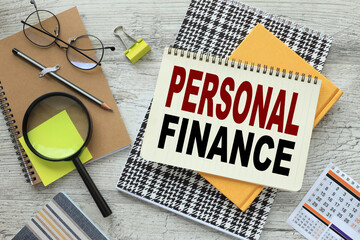 personal finance text on a notebook with a spiral in the middle of the table near glasses and a...