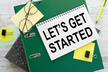 LET'S GET STARTED text on the page on a green folder near stickers on the work desk.