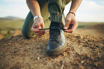 Hands, tie shoes and hiking in nature for travel, training or adventure outdoor. Fitness, sports and person tying laces on sneakers to start workout, walk or running, cardio or workout in countryside - Powered by Adobe