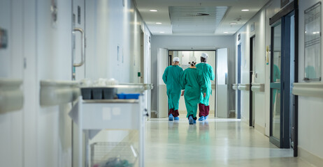 Diverse male and female surgeons wearing surgical gowns walking in corridor at hospital, copy space