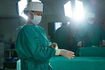 Asian female surgeon wearing medical gloves in operating theatre at hospital
