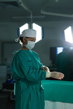 Asian female surgeon wearing medical gloves in operating theatre at hospital