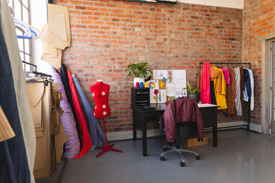 Designs on desk, colourful clothes and fabric in sunny studio