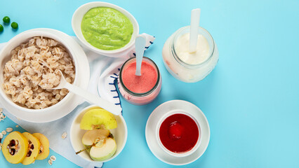 Bowls with healthy baby food on blue background.