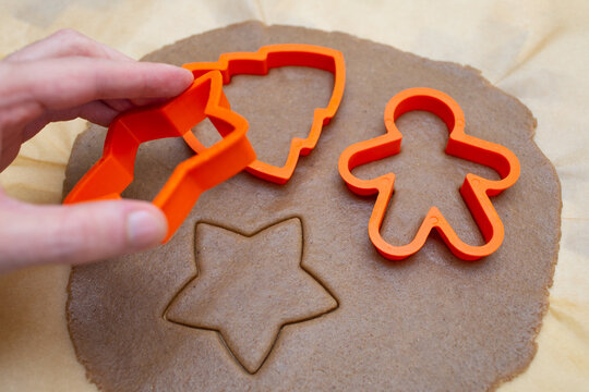 Man prepares Christmas gingerbread in the shape of a man, a star and a tree. Festive pastries for New Year and Christmas. The cooking process. Squeezes gingerbread out of the dough.