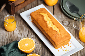 Popular biscuit dessert called Pound cake with white topping, served with oranges on rustic wooden...