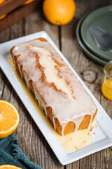 Popular biscuit dessert called Pound cake with white topping, served with oranges on rustic wooden background