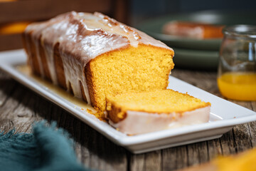 Popular biscuit dessert called Pound cake with white topping, served with oranges on rustic wooden background