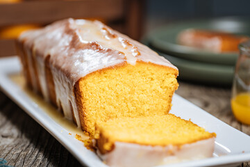 Popular biscuit dessert called Pound cake with white topping, served with oranges on rustic wooden background