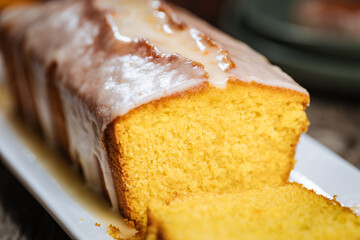 Popular biscuit dessert called Pound cake with white topping, served with oranges on rustic wooden background