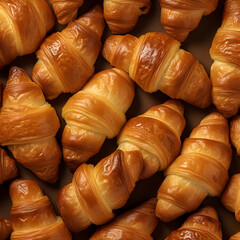 Close-up of freshly baked tasty croissants as background, placed in rows on a black tray. Food concept. Warm Fresh Buttery Croissants and Rolls.