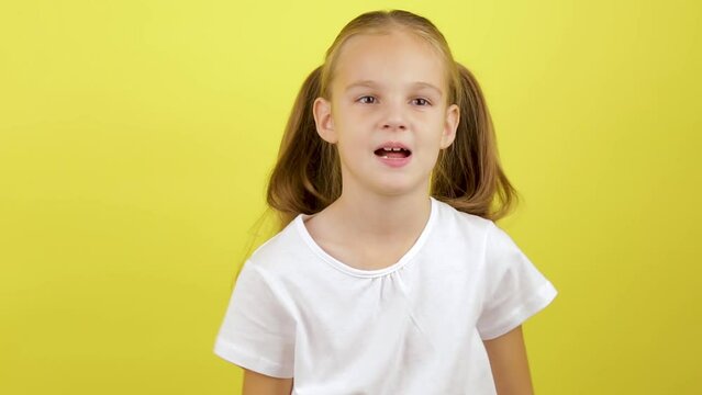 Angry dissatisfied little kid girl 7-8 years old in white t-shirt isolated on yellow background studio. Childhood lifestyle concept. Screaming swearing.