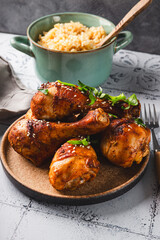 Chicken drumsticks with sesame seeds and rice, Asian cooked chicken on the table vertical photo