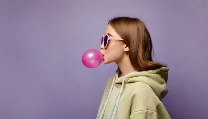 Foto op Plexiglas een igen girl wear stylish trendy sunglasses and hoodie blowing bubble gum profile side view, pretty young woman fashion cool model with bubblegum 80s at party purple studio background © Marko