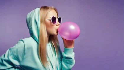 Poster een igen girl wear stylish trendy sunglasses and hoodie blowing bubble gum profile side view, pretty young woman fashion cool model with bubblegum 80s at party purple studio background © Marko
