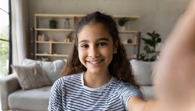 Happy Pretty Hispanic Gen Z Teen Girl Holding Smartphone Looking At Camera Taking Selfie Shot For Social Media, Making Video Call At Home By Virtual Mobile App. Close Up Face Headshot Portrait