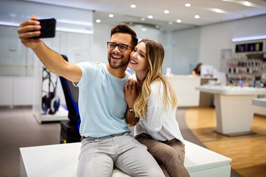 Smiling couple have fun using smartphone, watch video on cellphone make self-portrait picture