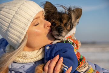 A dog owner kisses her pet in the muzzle.