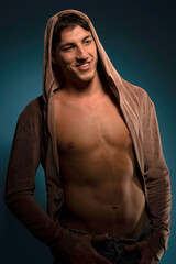 muscular smiling guy with a hood on dark blue background