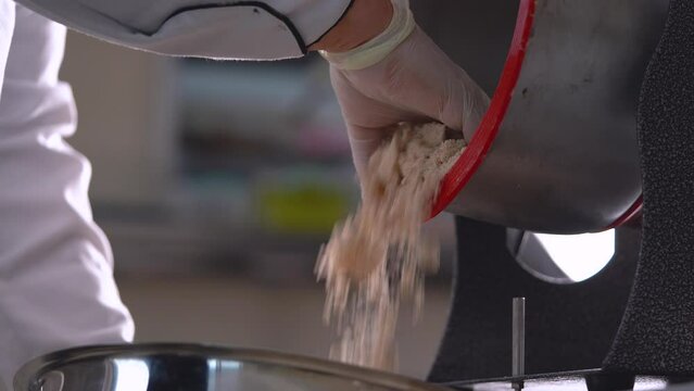 A French pastry chef unloads ground almonds from a grain milling machine