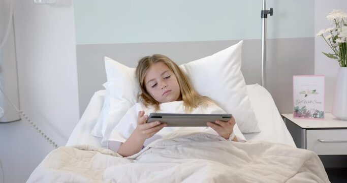 Tired caucasian girl patient lying in hospital bed using tablet, slow motion