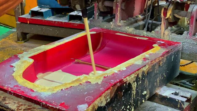 Chemical liquid is poured into the mold. The hose that releases yellow chemical fluid. Production process of foam rubber.