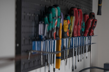 Selective focus of various screwdriver tools hanging on the wall and kept in holders in the garage