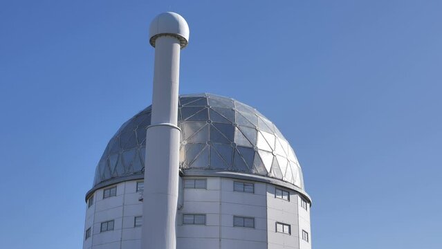 Shiny dome of SALT telescope rotates against cloudless blue sky