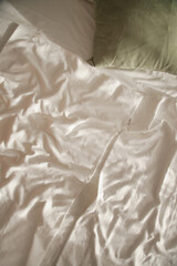 Messy bed. White cotton unmad blanket and sheets on bed.