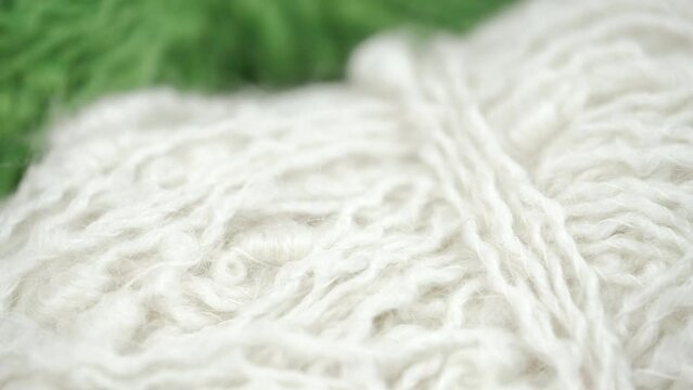 rotation of skeins bright white and green wool yarn. closeup. materials for needlework and crocheting or knitting warm and cozy products for winter. concept of women leisure. women hobby. macro.
