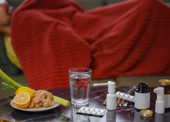 Ginger, lemon, onion and different drugs on table on background sick man. Alternative remedies and traditional pills to treat colds and flu. Natural medicine vs conventional medicine concept
