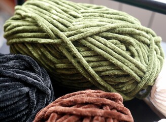 Photo of plush yarn skeins - green, black, and brown. Materials for crafts, knitting, crocheting.