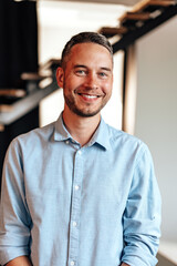 Confident young businessman standing near wooden ladder portrait