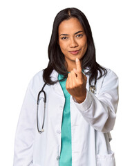 Young Filipina doctor with stethoscope in studio pointing with finger at you as if inviting come closer.