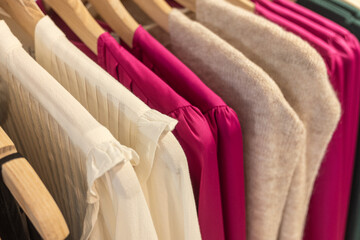 selective focus blouses and sweaters hanging from hangers in a boutique