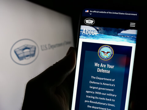 Stuttgart, Germany - 10-29-2023: Person holding smartphone with webpage of United States Department of Defense (DoD) in front of logo. Focus on center of phone display.