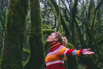 Side view of happy tourist enjoying green forest woods and trees opening arms and outstretching with smile expression and serene wellbeing. Healthy nature lifestyle people outdoors leisure adventure