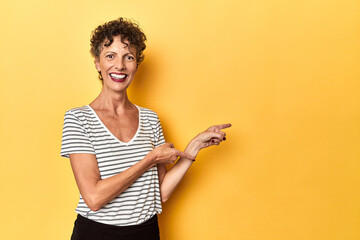 Mid-aged caucasian woman on vibrant yellow excited pointing with forefingers away.