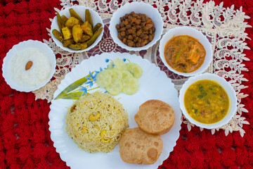 North Indian Thali without Onion Garlic . Indian Food including pulav poori dal paneer chana aloo sabzi and kheer . Food Platter Top View