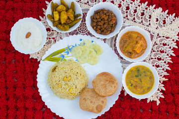 North Indian Thali without Onion Garlic . Indian Food including pulav poori dal paneer chana aloo sabzi and kheer . Food Platter Top View