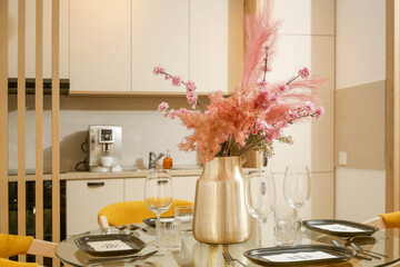 Dining table in the kitchen with pink flowers bouquet in the vase