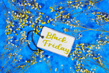 Black Friday Sale tag concept with yellow and white gypsophila on blue grunge background