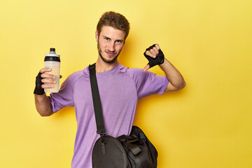 Caucasian athlete with gym gear on yellow feels proud and self confident, example to follow.